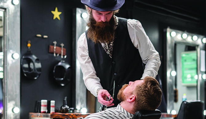 Barber cutting beard in barber shop