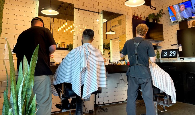 Two barbers on the floor cutting hair