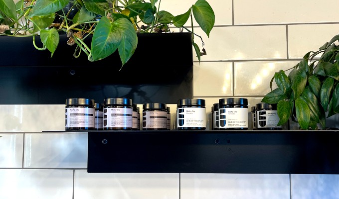 Hair products for men are being displayed on a shelf surrounded by pot plants 