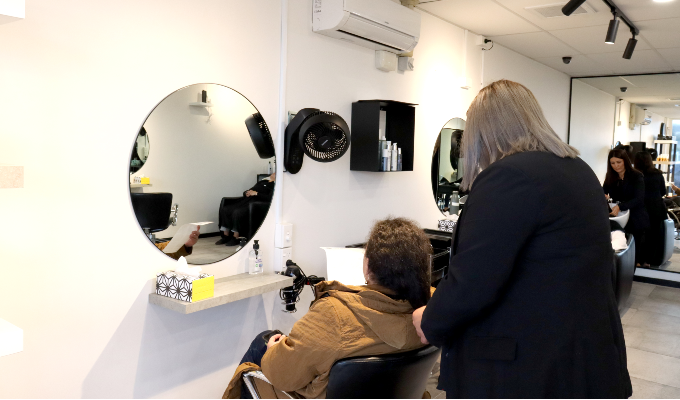 A stylist brushing her client's hair in front of a mirror